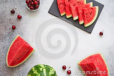 Summer berries frame. Slices of juicy watermelon on the black plate, cherries and pieces of watermelon on the concrete background. Stock Photo