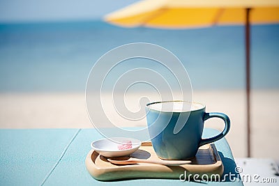 Summer blue coffee Latte cup by the beach with yellow umbrella background Stock Photo