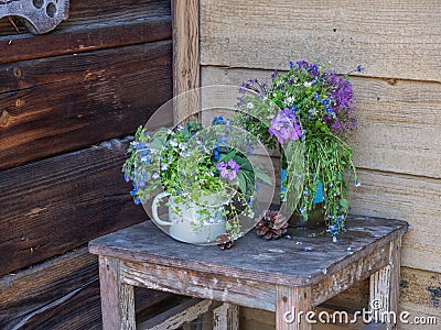 Summer bouquet of small wildflowers on an old wooden stool on the porch of a wooden house Stock Photo