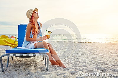 Summer break done right. an attractive young woman lounging on the beach and enjoying a cocktail. Stock Photo