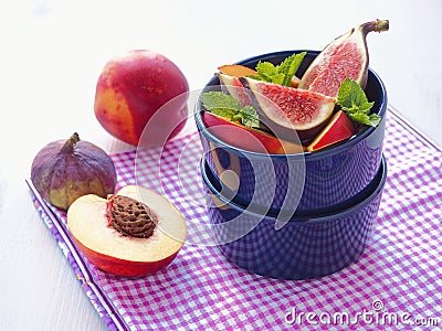 Summer breakfast. Ripe fruits with mint leaves and thyme sprig in violet vase. Fruit salad. Assorted summer fruits. Figs and peach Stock Photo