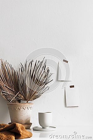 Summer breakfast still life. Cup of coffee and dry palm leaves in flower pot on table. Empty notepads and posters Stock Photo