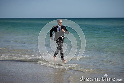 Summer business. Freelancer run on summer sea beach. Businessman in wet suit jump in sea water. Crazy business summer Stock Photo