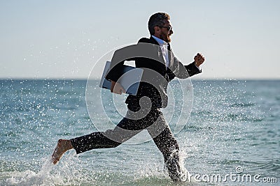 Summer business. Freelancer run on summer sea beach. Businessman in wet suit jump in sea water. Crazy business summer Stock Photo