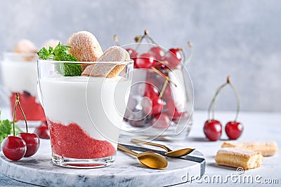 Summer cherry puff pastry with savoiardi cookies and cream cheese in glass on light grey background. Traditional tiramisu cake wit Stock Photo