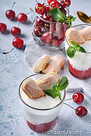 Summer cherry puff pastry with savoiardi cookies and cream cheese in glass on light grey background. Traditional tiramisu cake wit Stock Photo