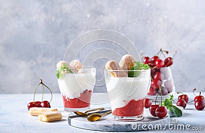 Summer cherry puff pastry with savoiardi cookies and cream cheese in glass on light grey background. Traditional tiramisu cake wit Stock Photo