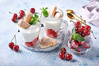 Summer cherry puff pastry with savoiardi cookies and cream cheese in glass on light grey background. Traditional tiramisu cake wit Stock Photo