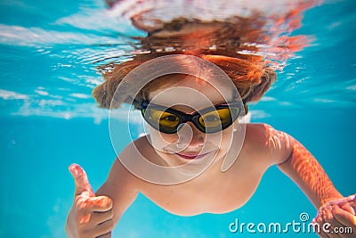 Summer child boy relax at aquapark. Summertime vacation. Little kid swim underwater in pool. Kid wearing summer goggles Stock Photo