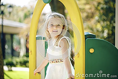 Summer, childhood, leisure, gesture and people concept - happy little girl playing on children playground Stock Photo