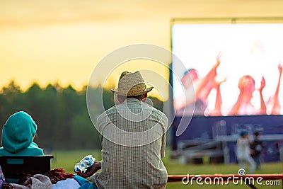 Summer cinema. A man in a straw hat is watching a movie in the open air Editorial Stock Photo