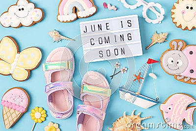 June is coming soon. Motivational quote on lightbox and cute summer symbols on blue background. Top view, Flat lay. Creative Stock Photo