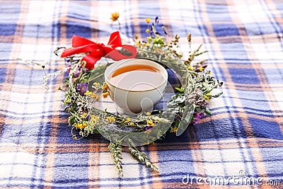 Wreath of wildflowers and tea cup on a checkered plaid background Stock Photo