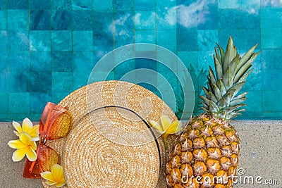 Summer concept. Hat, glasses, pineapple, flowers by the pool. Stock Photo