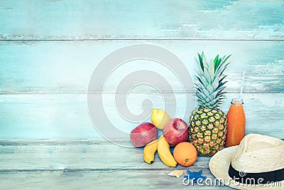 Summer concept stillife - a pile of fresh fruits, straw hat and a bottle of multivitamin juice in front of a blue rustic wooden Stock Photo