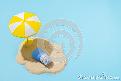 Summer concept. Sunscreen cream on sand and sun umbrella on blue background. Skin care concept in summer Stock Photo