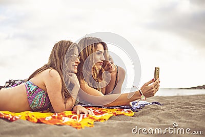 Summer concept tourists with three friends girls lay down on the beach for a sunbath together taking selfie picture with smart Stock Photo