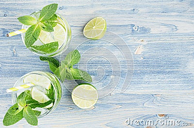 Summer cool lemonade in two wet glasses with mint, lime, ice, straw on soft shabby blue wood board, copy space, top view. Stock Photo