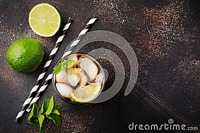 Summer cooling alcoholic beverage from cola, whiskey, lime and liqueur in glass on dark concrete old background. Stock Photo