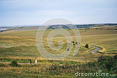 A summer country road runs across fields of chalk grassland at Beachy Head on the Sussex coast of the South Downs hills Editorial Stock Photo