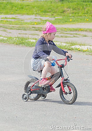 Summer day the child rides the girl on the bike. Stock Photo