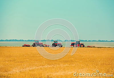 Summer day three tractors to plow, plow the soil on sloping, cornfield. Stock Photo