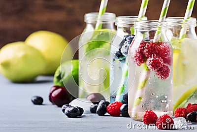 Summer drinks set. Berry, fruit and citrus non-alcoholic refreshing ice cold beverages and cocktails in glass bottles on blue Stock Photo