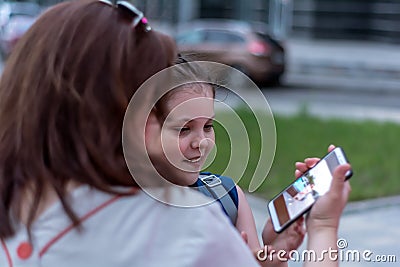 Summer evening. Holidays. Mother and daughter watch nice photo on smartphone Stock Photo