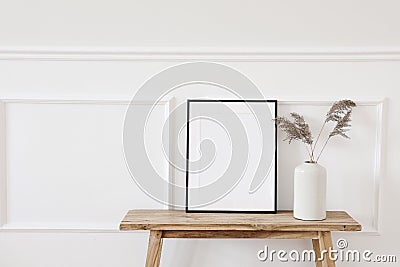 Summer, fall still life photo. Vase with dry reed, grass on old wooden bench. Blank black picture frame mockup. White Stock Photo