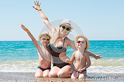 Mother and two sons in hats sitting on the beach.Summer family vacation. Stock Photo