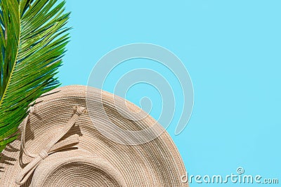 Summer fashion tropical concept. Women`s female beachwear straw hat green palm leaf on mint blue background Stock Photo