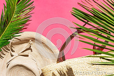 Summer fashion tropical vacation concept. Women`s female beachwear straw hat wicker bag green palm leaves on fuchsia pink Stock Photo