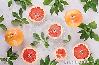 Summer fresh background - round slices pink grapefruits and green leaves on white wood board, top view, pattern. Stock Photo