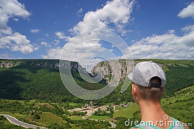 Summer hiking in the mountains. Young tourist man in a cap looking on mountain Stock Photo