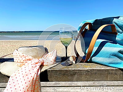 Summer holiday glass of wine on restaurant table , women hat with bow beachwear and seashell and blue bag , turquoise ocean wat Stock Photo