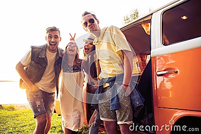 Summer holidays, road trip, vacation, travel and people concept - smiling young hippie friends having fun over minivan Stock Photo