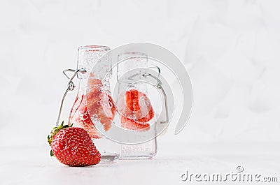 Summer homemade drinks - infused strawberry water with sliced berry, soda in yoke bottles in soft light white interior, copy space Stock Photo