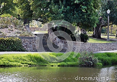Summer landscape in the park with a stone staircase, path, river bank, green grass and trees Stock Photo