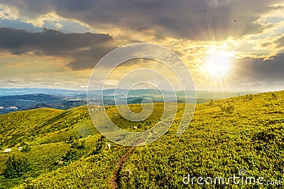 summer landscape at sunset. path through hillside meadow on the mountain ridge under the cloudy sky Stock Photo