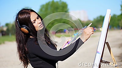 summer, near river, on beach. at sunrise, a beautiful woman artist holds a brush in her hand, draws a picture. she Stock Photo