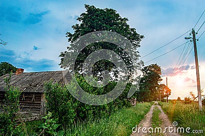 Summer orange sunset in a small Russian village. Rustic summer landscape. Grit effect. Wooden rural hut in the village Stock Photo