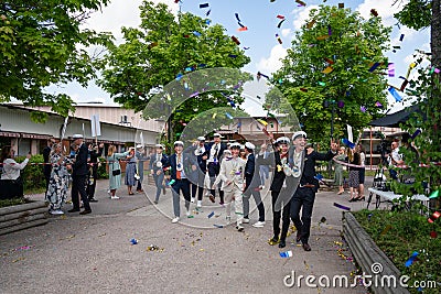 Summer outdoor graduation ceremony. Many students with parents and confetti in the air. Editorial Stock Photo