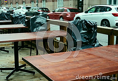 Summer is over, plastic-covered chairs in empty street cafe Stock Photo