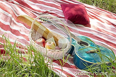 Summer picnic basket with apples and guitar lie on plaid with pillows heat Stock Photo