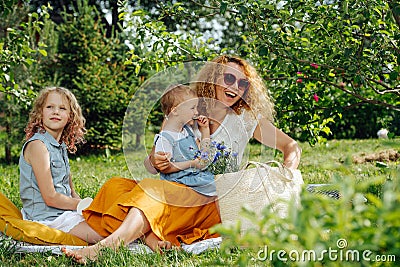 Family picnic on grass in the gardens under gentle shade of trees Stock Photo
