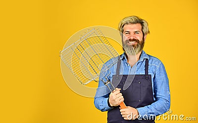 Summer picnic. Hipster dyed beard promoting bbq equipment. Cooking healthy. Man in apron hold barbecue grill. Tools for Stock Photo