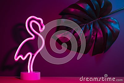 Summer pink flamingo and monstera leaf with neon pink and blue light.vacation background Stock Photo