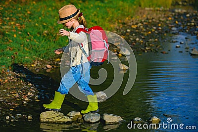 Summer portrait of happy cute child girl traveling and camp. Little girl child walking in river. Summer at countryside Stock Photo