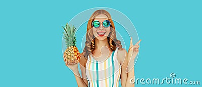 Summer portrait of happy smiling woman with pineapple wearing sunglasses posing on blue background Stock Photo