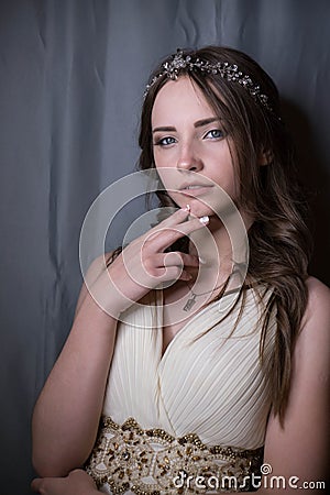 Summer portrait of young beautiful lady wearing long white evening dress posing in the studio. Stock Photo